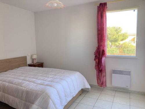 une chambre avec un lit blanc et une fenêtre dans l'établissement Villa LES LAURIERS avec terrasse et jardin proche plage, à Narbonne-Plage