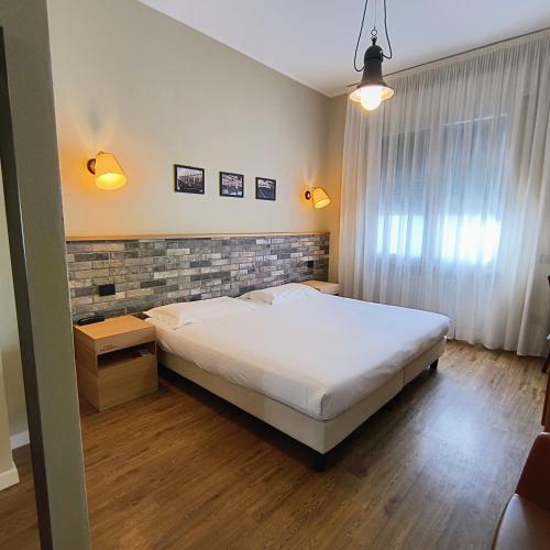 a bedroom with a white bed and a brick wall at Hotel Miramonti in Schio