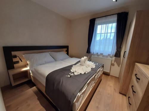 a bedroom with a bed with white sheets and a window at Residence Klažary u Žumberka - Terasové apartmány in Kamenná