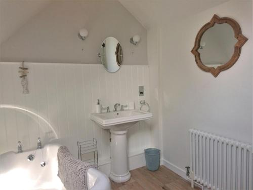 a bathroom with a sink and a tub and a mirror at Pass the Keys The Pippins a Cotswold cottage and garden parking in Stow on the Wold