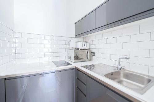 uma cozinha branca com um lavatório e um micro-ondas em Edinburgh Castle Apartments em Edimburgo