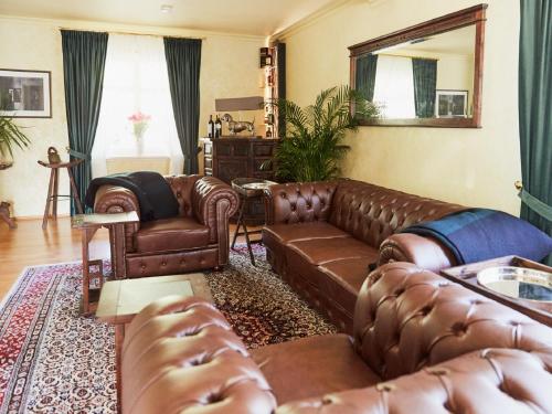 a living room with brown leather furniture and a mirror at BnB Rauschenberg in Rauschenberg