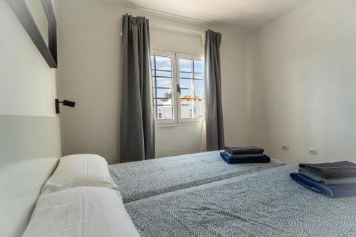 Habitación blanca con cama y ventana en Las Casitas de Corralejo en Corralejo