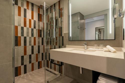 a bathroom with a sink and a shower with a mirror at Radisson Safari Hotel Hoedspruit in Hoedspruit