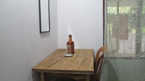 Anuhas Family Resort & Water House في أنورادابورا: طاولة خشبية عليها زجاجة وكأس