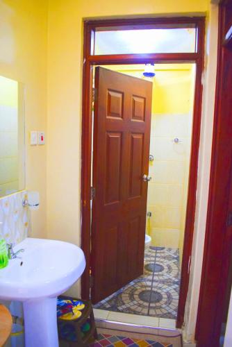 a bathroom with a toilet and a sink and a door at Casabella Apartment - Pristine Homes,Tom Mboya in Kisumu