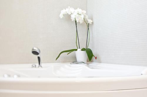 a vase with white flowers sitting on a bathroom sink at Al Tezzon Hotel in Camposampiero