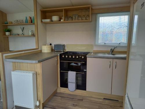 a small kitchen with a stove and a sink at Lindens on the Lido in Knaresborough
