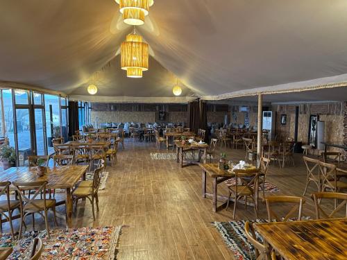 een restaurant met tafels en stoelen en een kroonluchter bij AGAFAY BIV FOLK & SPA by WE CAMPS in Ourika
