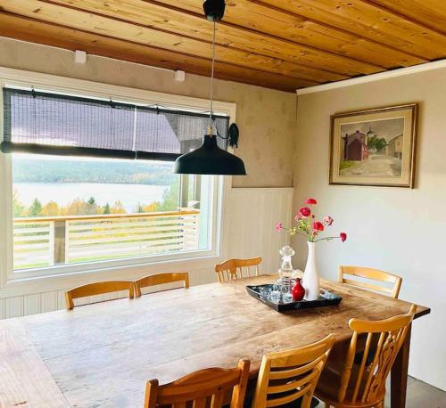 a dining room with a wooden table with chairs and a large window at Villa Kakelbont! in Föllinge