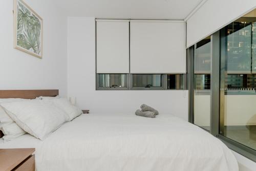 Schlafzimmer mit einem großen weißen Bett und einem Fenster in der Unterkunft Modern 2 Bedroom Apartment Darling Square in Sydney