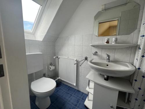 a white bathroom with a toilet and a sink at STOE 14a Gästehaus Iden, App 3 in Niendorf
