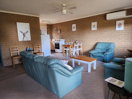 a living room with blue furniture and a kitchen at Pomonal Cottages Grampians in Halls Gap