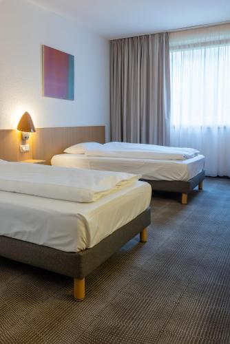 a hotel room with three beds in a room at Novotel Düsseldorf City West in Düsseldorf