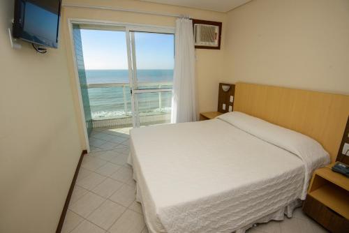 a bedroom with a bed and a view of the ocean at Hotel Plaza Mar in Vila Velha