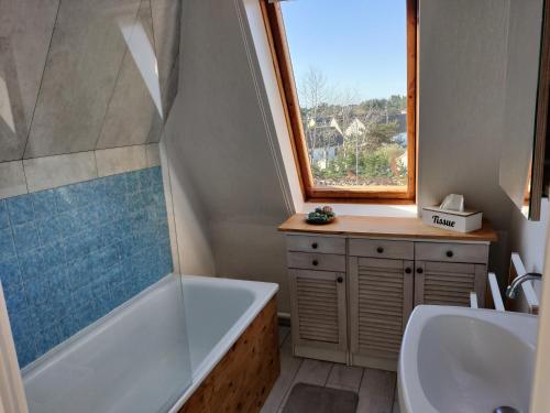 baño con bañera, lavabo y ventana en Bel appartement refait à neuf, calme et ensoleillé, en Cabourg