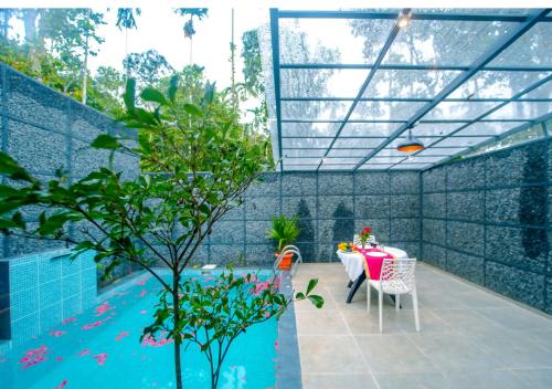 a patio with a table and a swimming pool at Wildside Jungle Retreat Wayanad Resort by VOYE HOMES in Wayanad