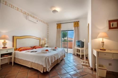 - une chambre avec un grand lit et une télévision dans l'établissement Martinhal Quinta Family Resort, à Quinta do Lago