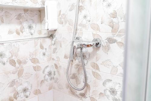 a shower in a bathroom with floral wallpaper at Guesthouse Močivnik in Okroglice