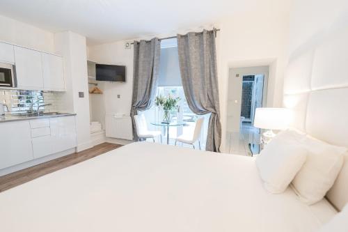 a white bedroom with a kitchen and a table at Edinburgh Castle Apartments in Edinburgh