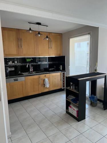 une cuisine avec des armoires en bois et un comptoir noir dans l'établissement 2-bedroom apartment (60m2), à Ivry-sur-Seine