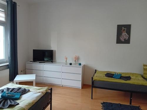 a bedroom with two beds and a dresser with a tv at Stellas Monteurwohnungen in Werdau