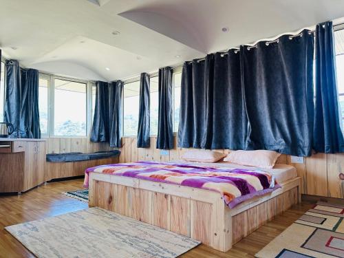1 dormitorio con cama de madera y cortinas negras en Dhauladhar Homes, en Dharamshala