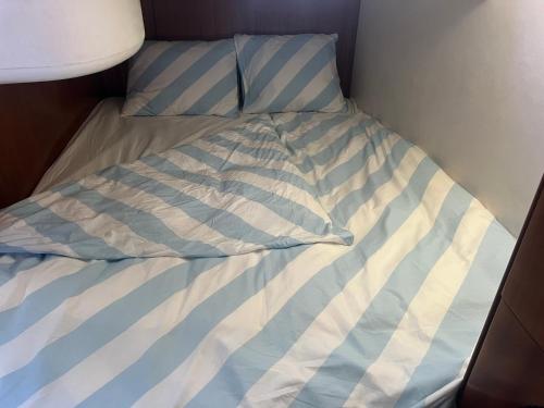a bed with a blue and white striped comforter at Maser II ( Excelente Mini Yate ) in Valencia