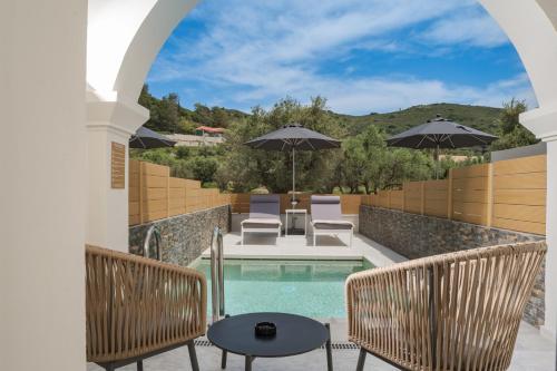 an outdoor patio with a pool and chairs and umbrellas at Nikon Boutique Hotel in Kalamaki