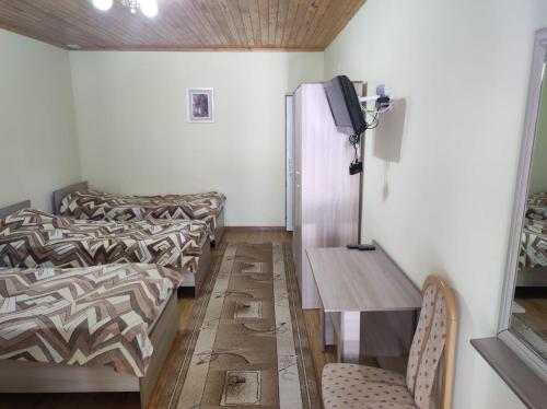 a room with two beds and a table and a tv at Бархатный Сезон in Cholpon-Ata