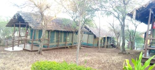 a house with a thatched roof in a forest at Lake Manyara View Luxury Tented Camp in Mto wa Mbu