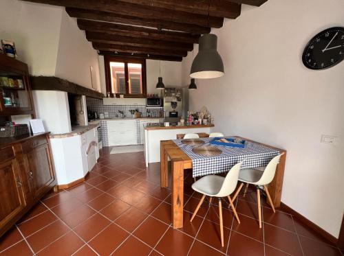 een keuken met een tafel en stoelen en een klok bij Crestudio Stanza accogliente vicino al Ponte Vecchio in Bassano del Grappa