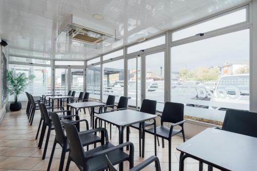 una fila de mesas y sillas en un restaurante con ventanas en Hotel Restaurante Cazador, en Pereiro