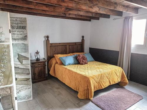 a bedroom with a bed with a yellow blanket and blue pillows at Casa Oasis in Teguise