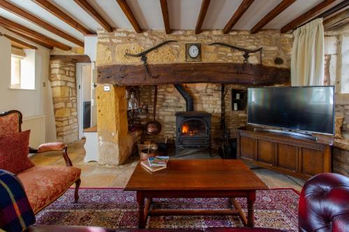 uma sala de estar com televisão e lareira em Graziers Cottage - character Cotswold cottage with inglenook, parking and pub nearby em Cheltenham