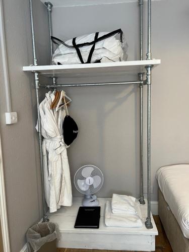 a shelf in a bedroom with a fan and clothes at White Horse in Maldon
