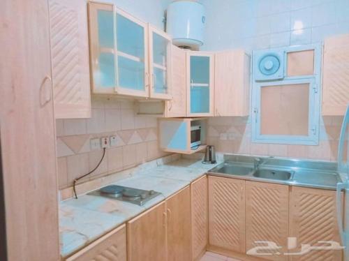 uma cozinha com armários de madeira e um lavatório em درة رواق em Riyadh