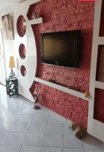 sala de estar con pared roja y TV de pantalla plana en Appart centre agadir vue sur mer proche de toutes commodités., en Agadir