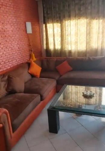 sala de estar con sofá marrón y mesa de cristal en Appart centre agadir vue sur mer proche de toutes commodités., en Agadir