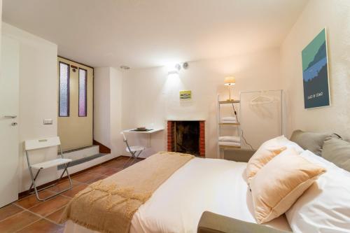 1 dormitorio con cama blanca y chimenea en Lilliput Apartment by Wonderful Italy, en Bellagio