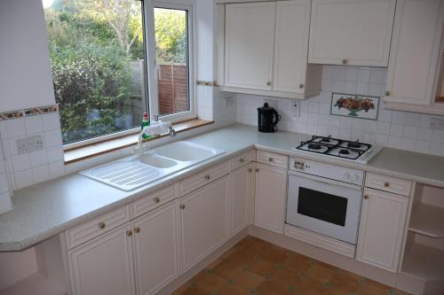 a kitchen with white cabinets and a sink and a window at Spacious 4 Bed Home Near NEC, JLR & Airport Parking for 3 Cars Ideal for Contractors! in Olton
