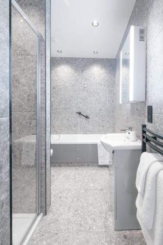 a bathroom with a shower and a sink and a tub at The Pillar Hotel in London
