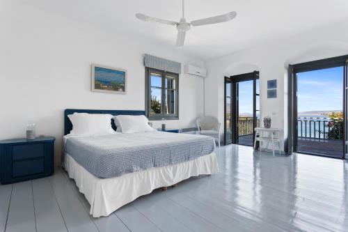 a white bedroom with a bed and a balcony at Villa Iris - Luxury traditional beachfront villa with swimming pool in Koilás