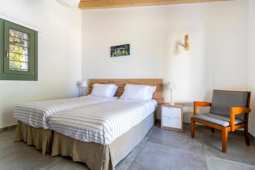 a bedroom with a bed and a chair at Villa Iris - Luxury traditional beachfront villa with swimming pool in Koilás