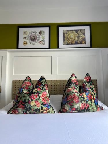 two pillows on a bed with three pictures on the wall at White Horse in Maldon