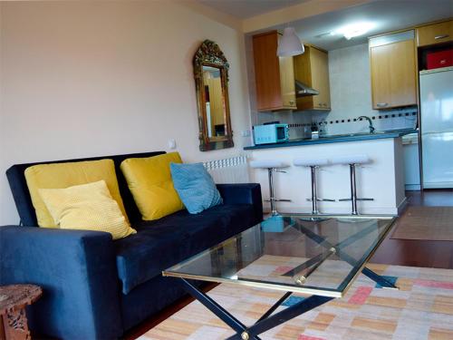 a living room with a blue couch and a glass table at Apartamentos Las Margas Sabiñánigo 3000 in Sabiñánigo