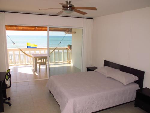 a bedroom with a bed and a balcony with the ocean at Los Sonidos de las Olas in Santa Marianita