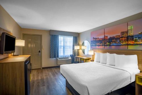 ein Hotelzimmer mit einem Bett und einem Flachbild-TV in der Unterkunft Days Inn by Wyndham Lonoke in Lonoke