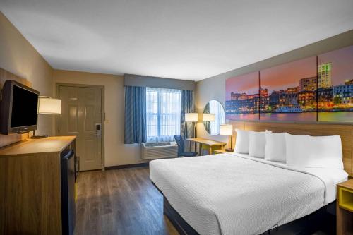 a hotel room with a bed and a flat screen tv at Days Inn by Wyndham Lonoke in Lonoke