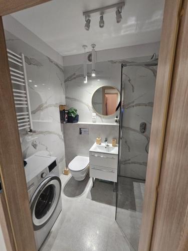 y baño con lavamanos y lavadora. en Apartament Panorama Miasta en Gdynia